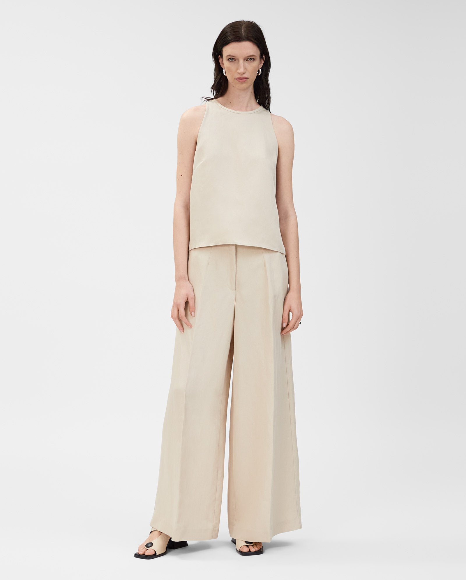 A woman models the IVY OAK TAILOR SUE Top with wide-leg beige linen-blend pants, featuring a concealed zip, standing against a plain white background.
