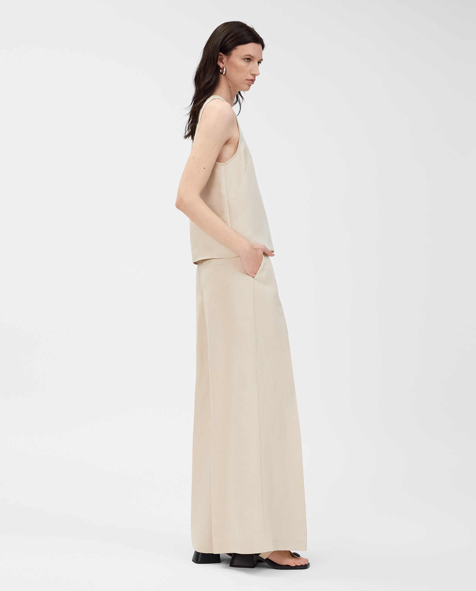 Woman wearing the IVY OAK TAILOR SUE Top and wide-leg beige linen-blend pants, standing sideways against a white background.