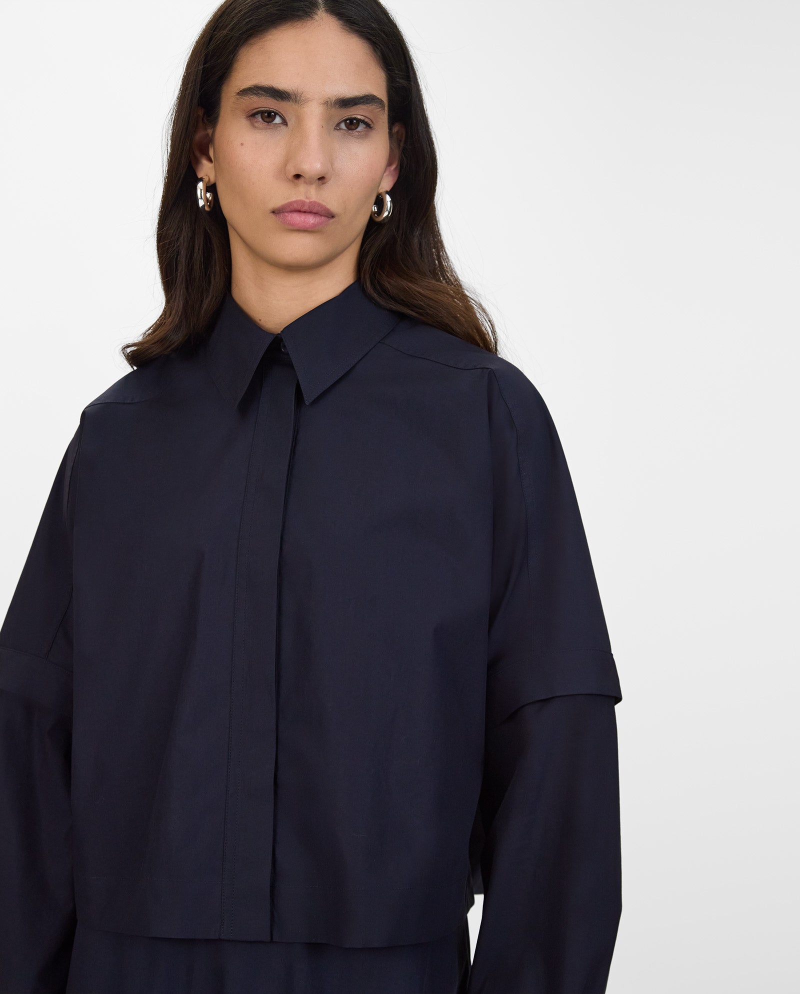 A woman with long dark hair wears the ELVIRA Shirt by IVY OAK in navy, looking serious against a plain backdrop.