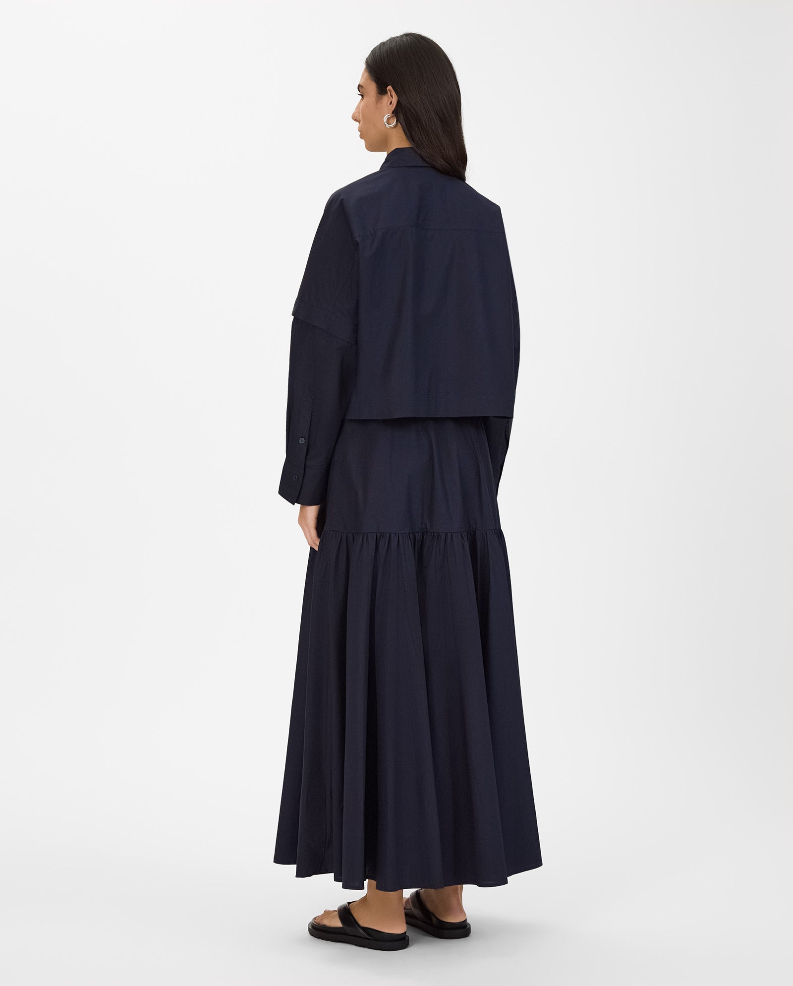 A woman stands with her back to the camera against a white background, wearing the IVY OAK ELVIRA Shirt paired with a long navy dress.