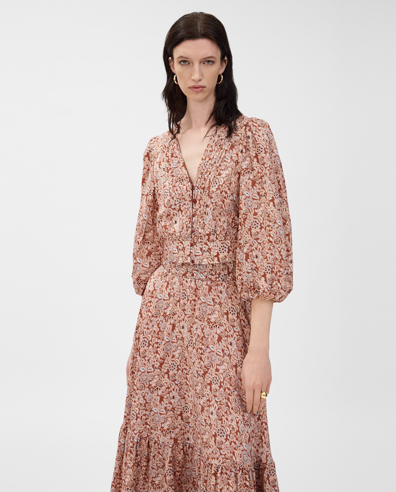 A woman wears the IVY OAK ENRICA Blouse, featuring a floral pattern and balloon sleeves, standing against a plain background.