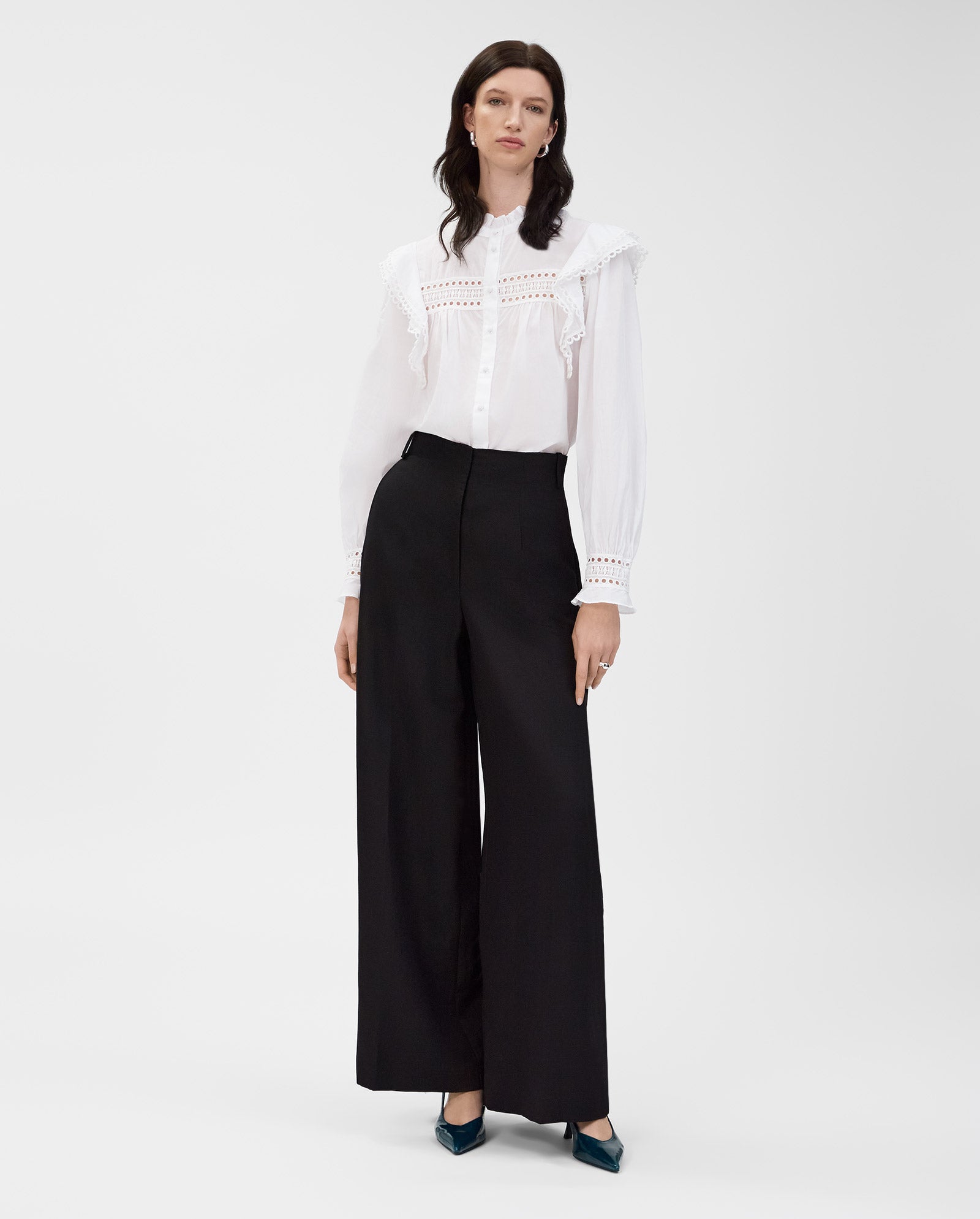 Woman in the IVY OAK EVELINA Blouse, crafted from cotton voile with lace tape details, paired with black wide-leg pants, standing against a plain background.