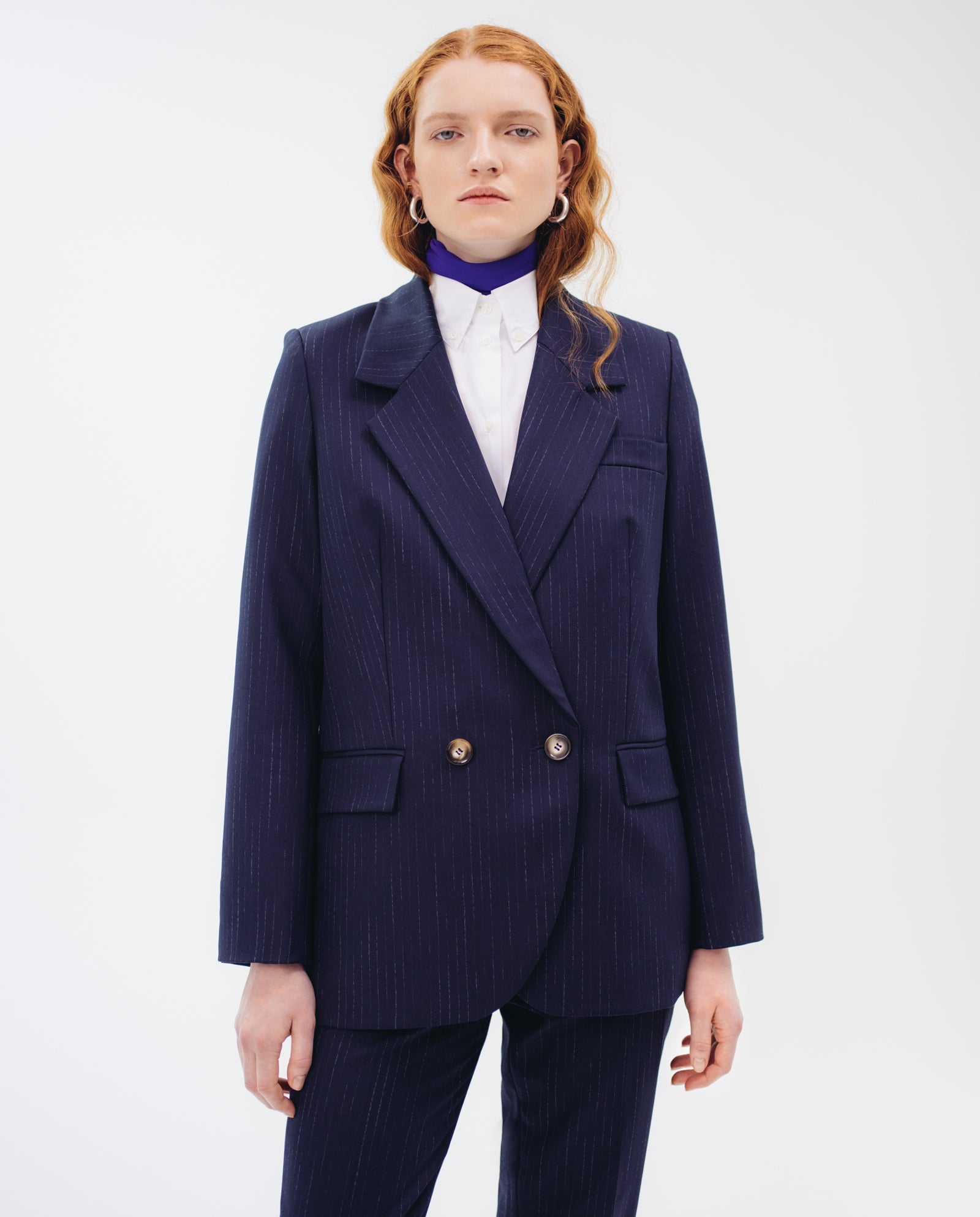 Person with long red hair wears the IVY OAK JANINA ANN Blazer, featuring navy pinstripes and piped pockets, over a white shirt against a plain white background.