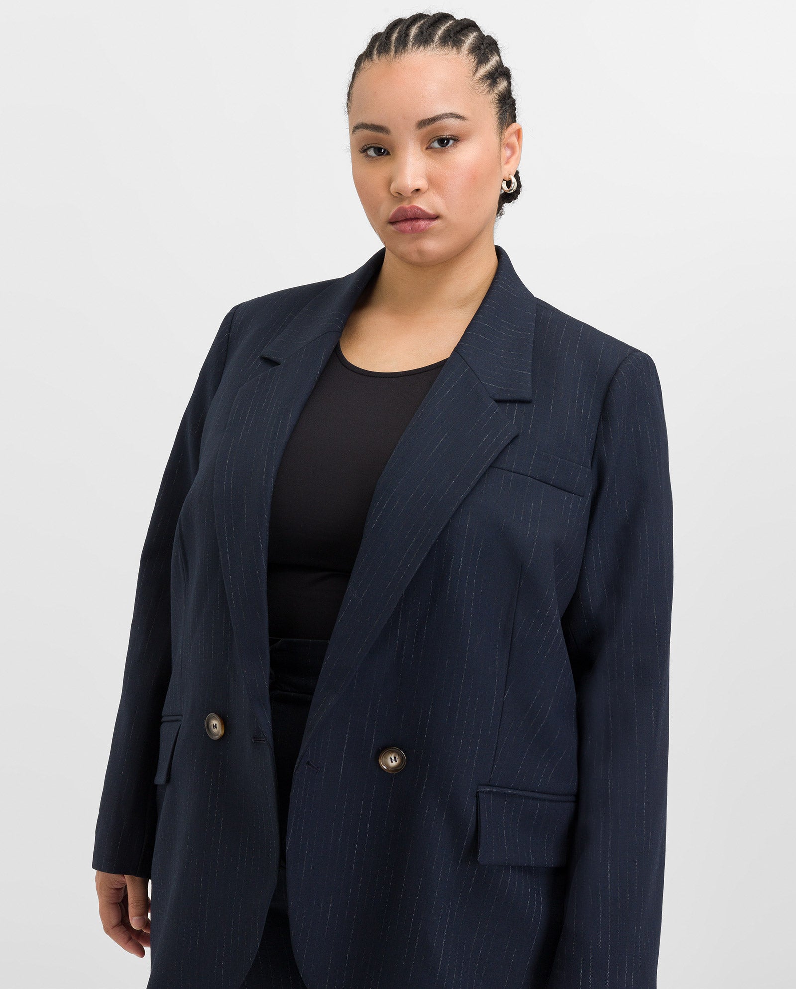 A woman with braided hair wears the IVY OAK JANINA ANN Blazer over a black top, standing against a plain light background.