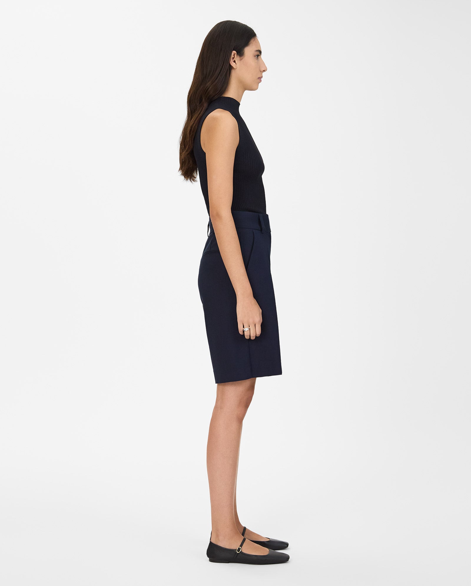 A woman stands in profile wearing IVY OAKs PEONY SUE Trousers, a sleeveless black top, and black flats.