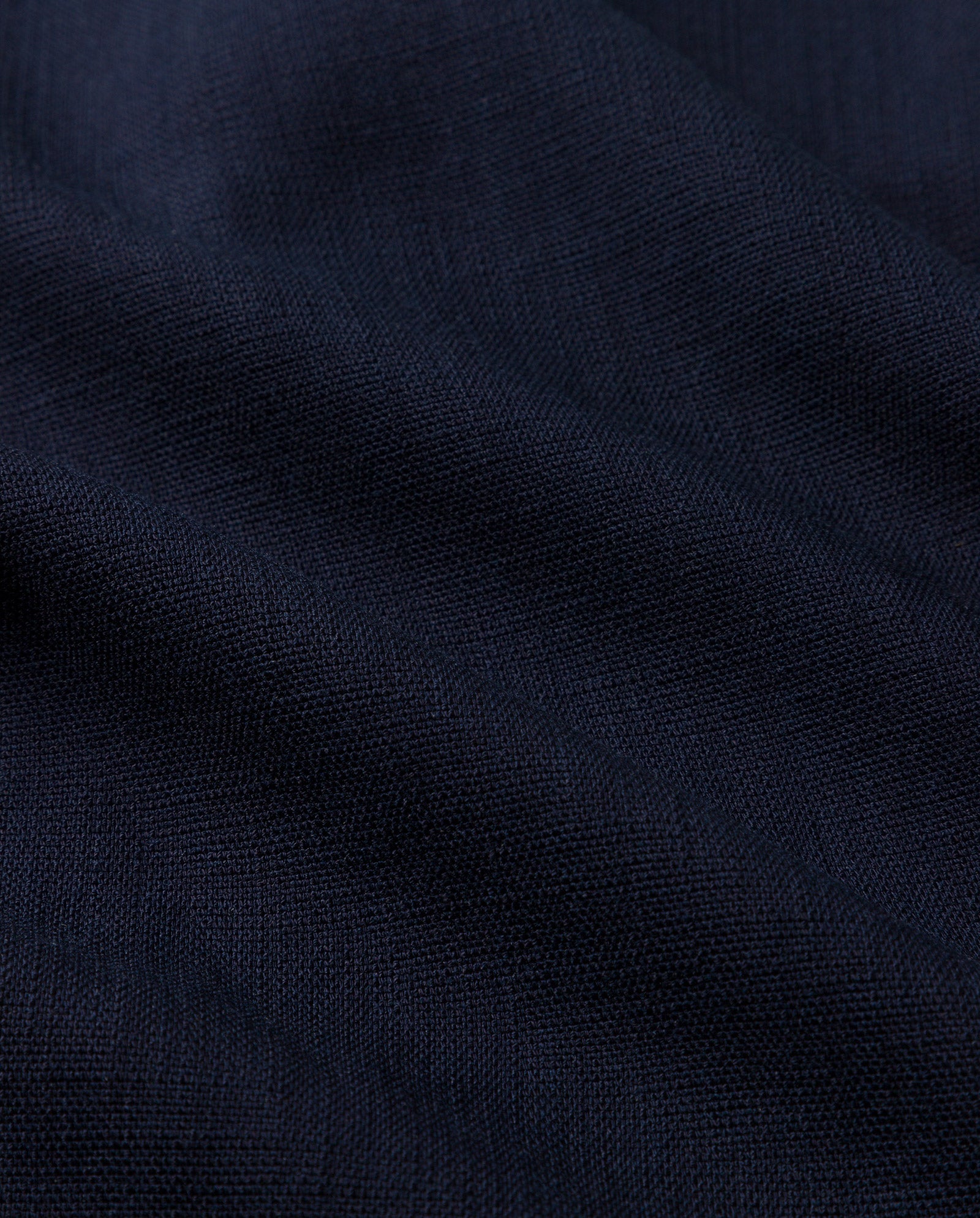 Close-up of dark navy blue fabric with visible texture and soft folds, reminiscent of the premium material featured in IVY OAK’s PRESCILLIA ANN Pants.