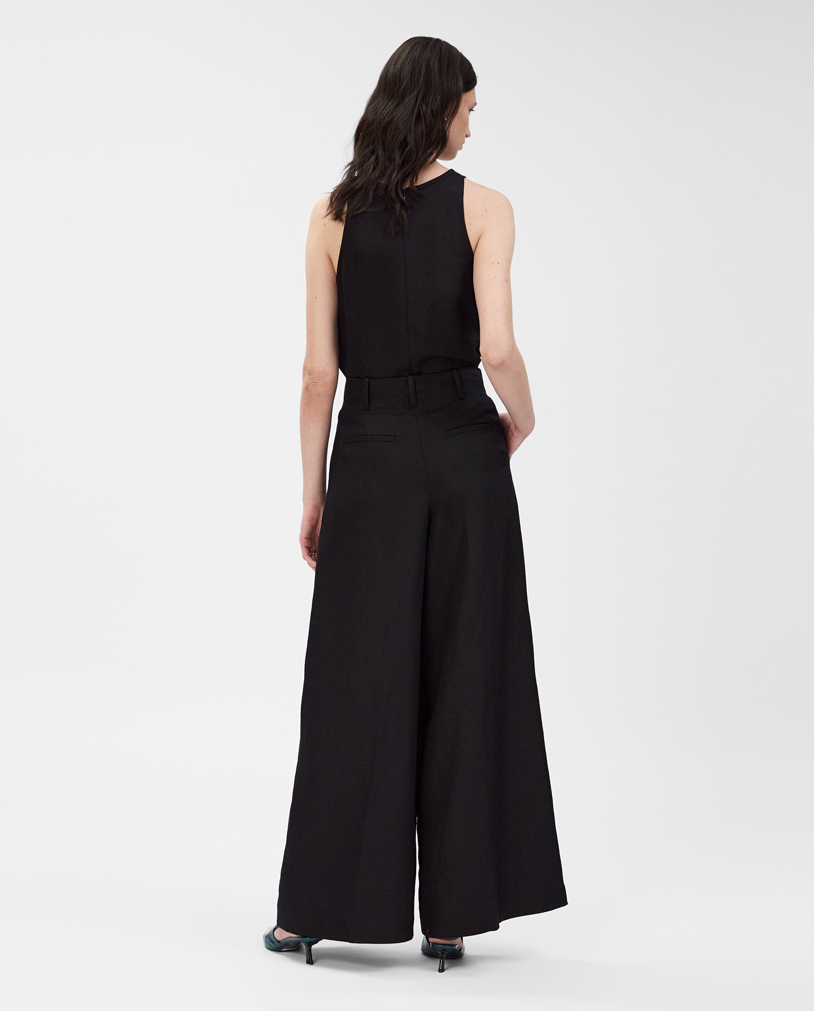 A woman is seen from the back wearing IVY OAKs PIERA Trousers with a sleeveless black top.