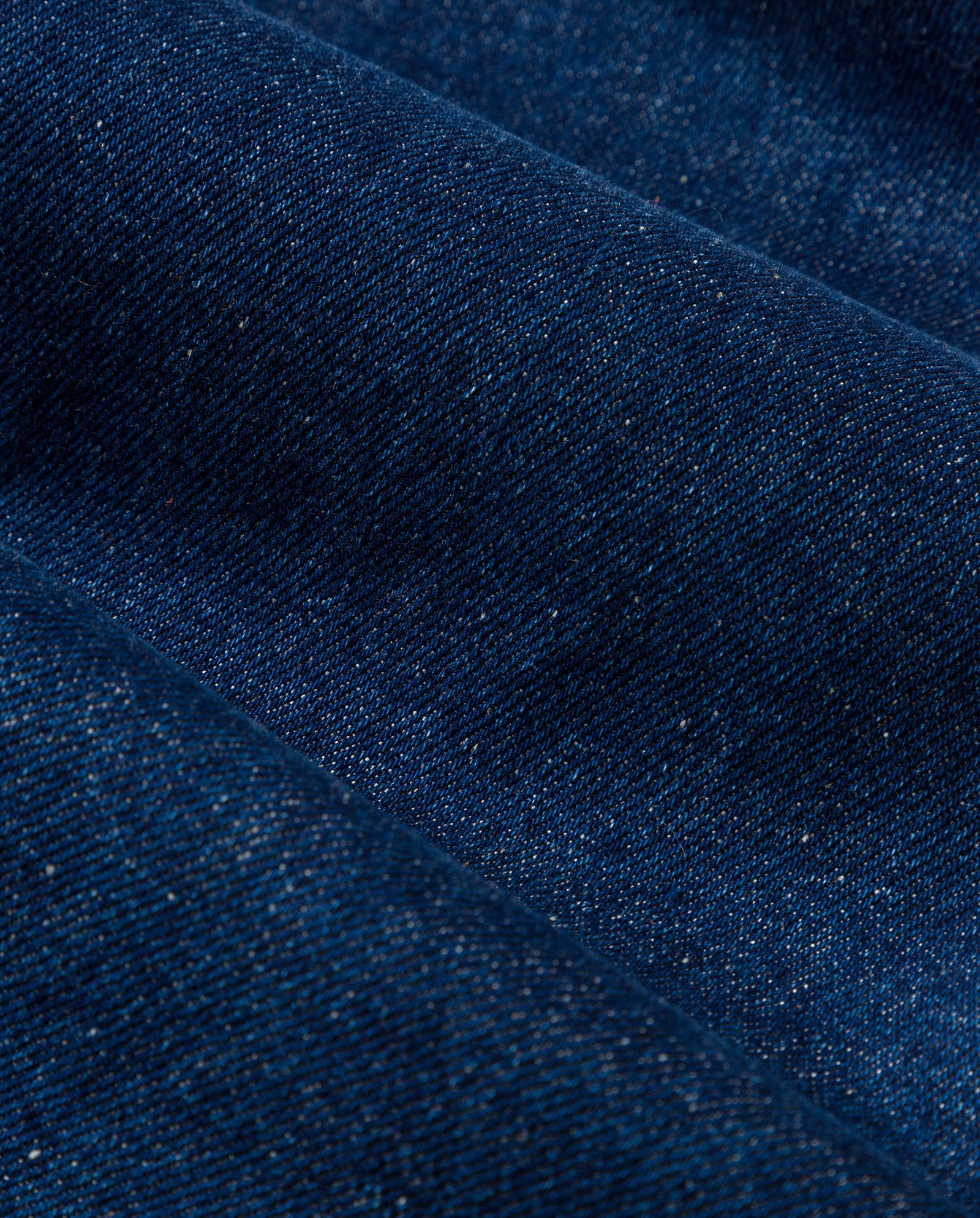 Close-up of IVY OAKs STEFANIE Skirt in dark blue denim, enriched with indigo dye and featuring a visible weave texture with diagonal folds.