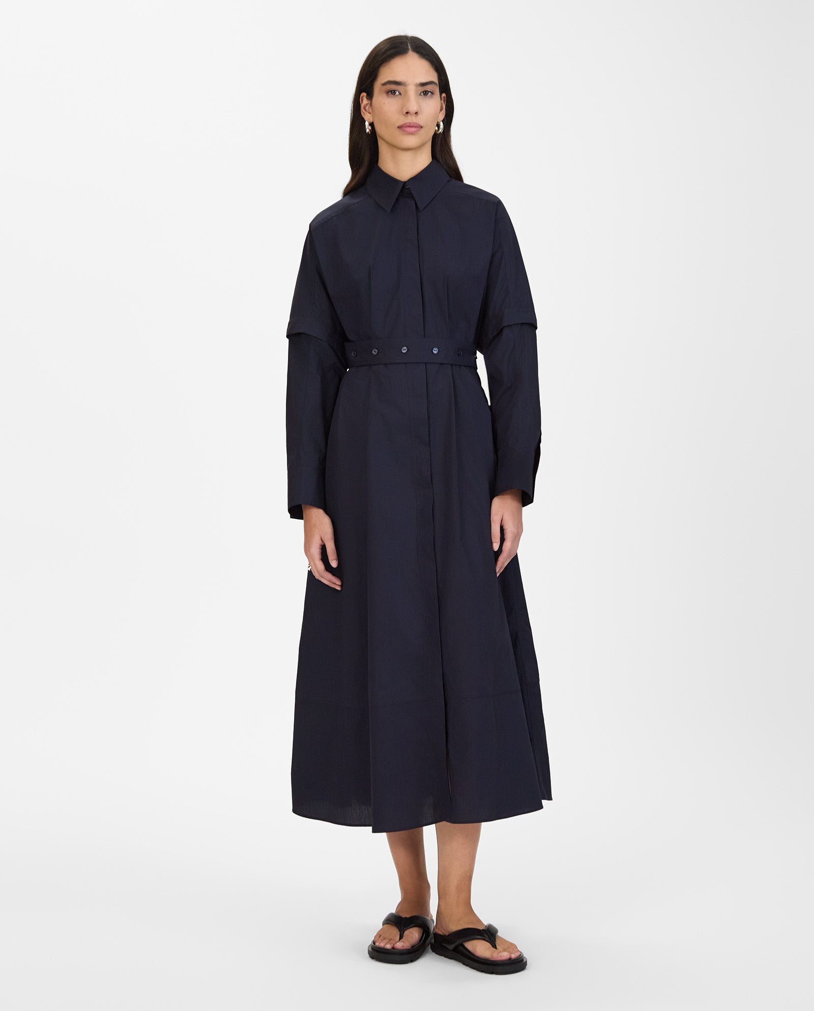 A woman wears the IVY OAK NORENA Dress with detachable long sleeves and black sandals, standing against a plain white background.