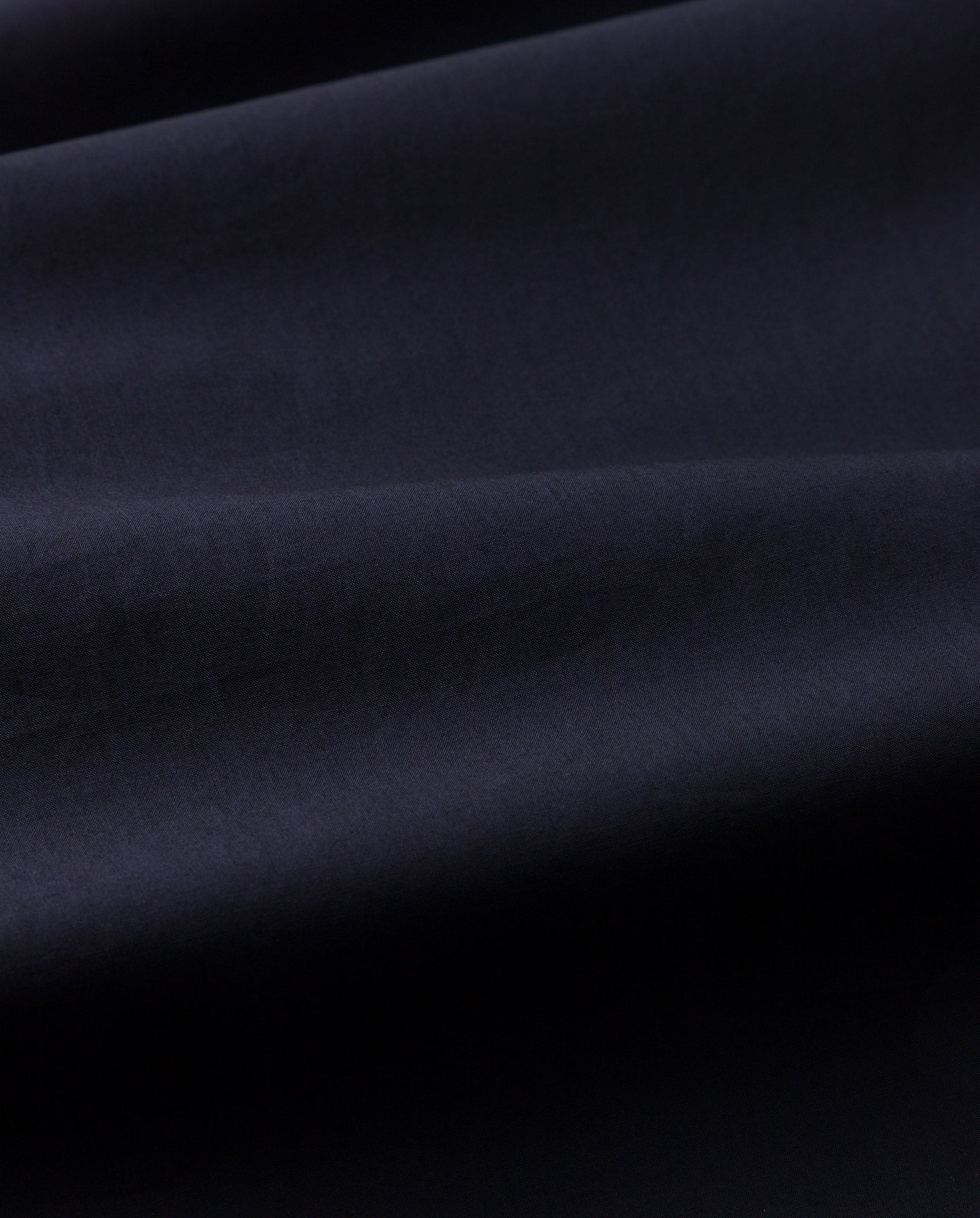 Close-up of smooth, dark navy blue fabric with gentle folds and soft texture, reminiscent of the luxurious feel found in the IVY OAK NORENA Dress.