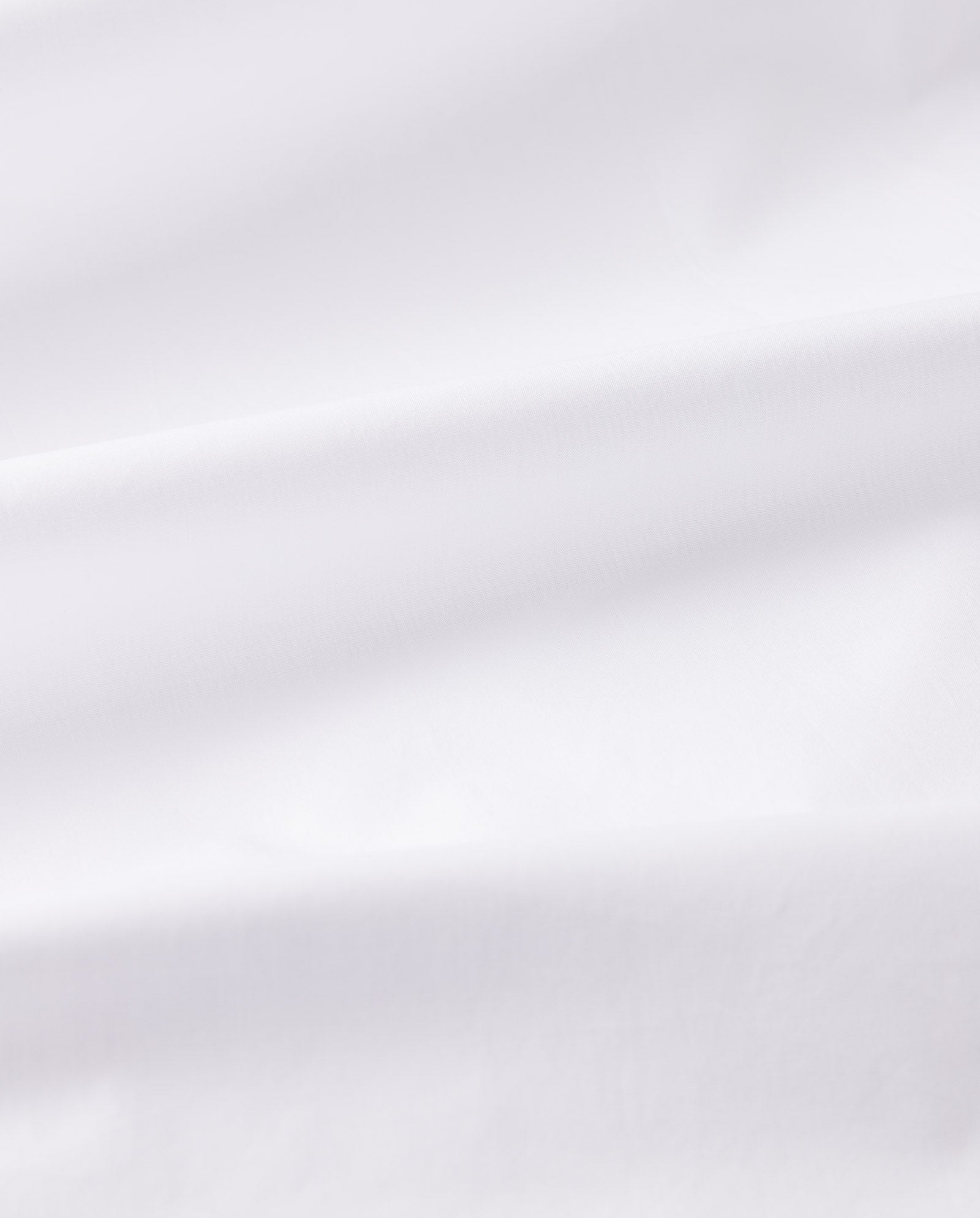 The NICOLINA Dress by IVY OAK features white fabric with soft folds and a smooth texture, forming a flowing A-line silhouette that creates gentle shadows along its maxi length.