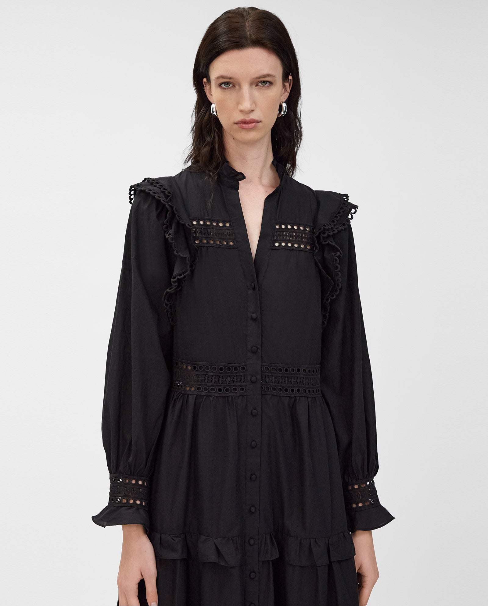 A woman wears the IVY OAK DENISA Dress, crafted from cotton voile with ruffle and lace tape details, standing against a plain background.