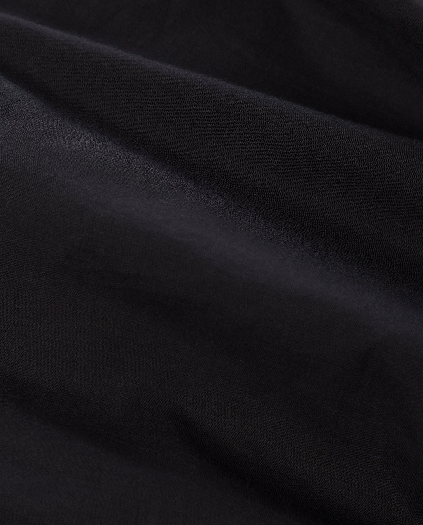 Close-up of black cotton voile fabric from the IVY OAK DENISA Dress, showcasing soft folds, subtle texture, and delicate lace tape details.