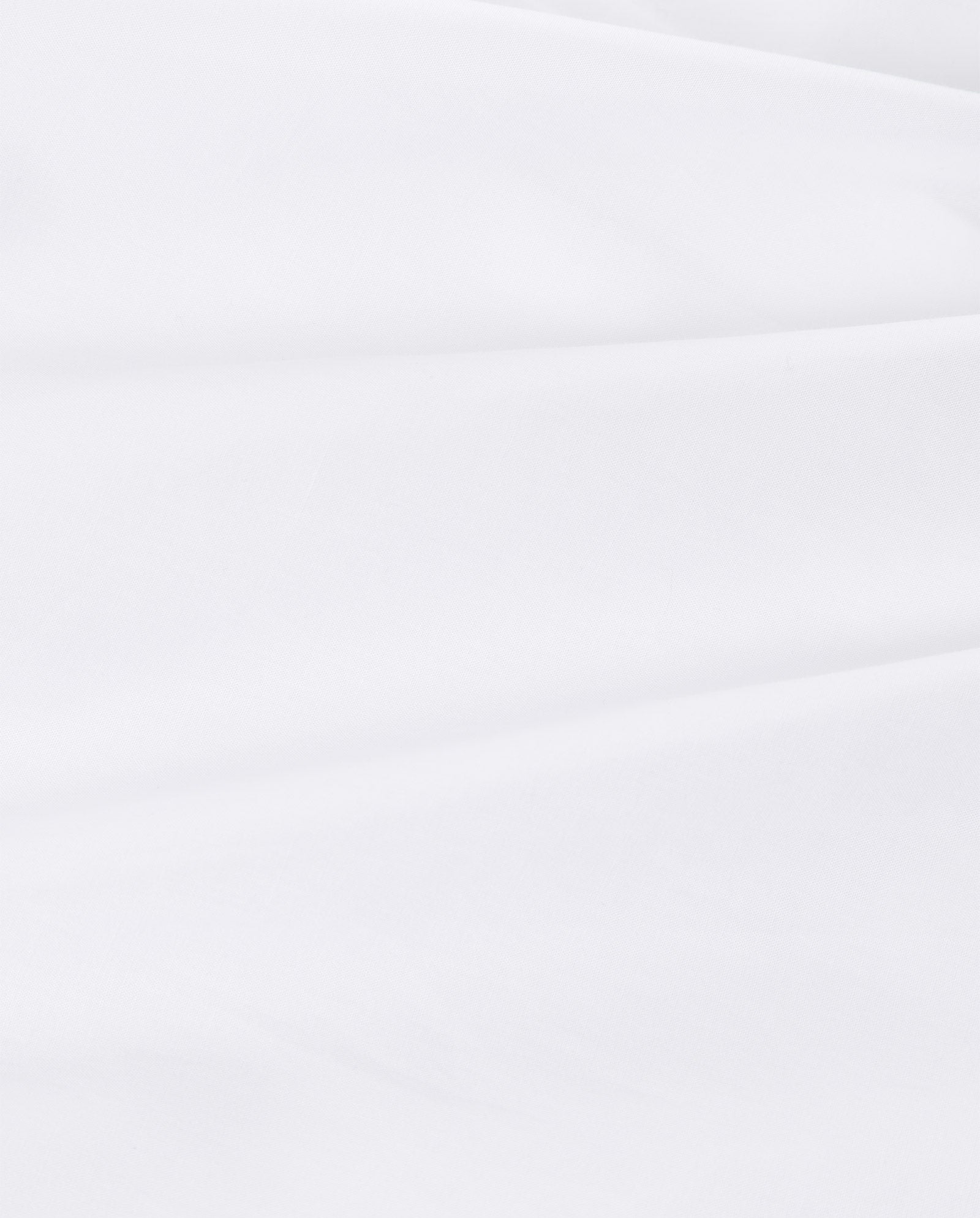 Close-up of the DENISA Dress by IVY OAK features smooth white fabric with gentle folds, ideal for refined details like covered buttons or lace tape. Soft shadows highlight its elegant texture.