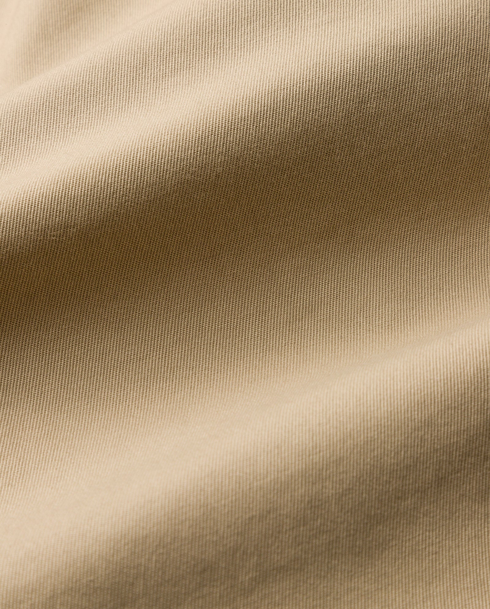 Close-up of beige fabric with a visible diagonal weave and soft folds—classic details featured in the IVY OAK JOANNE Jacket, reminiscent of refined trench designs.