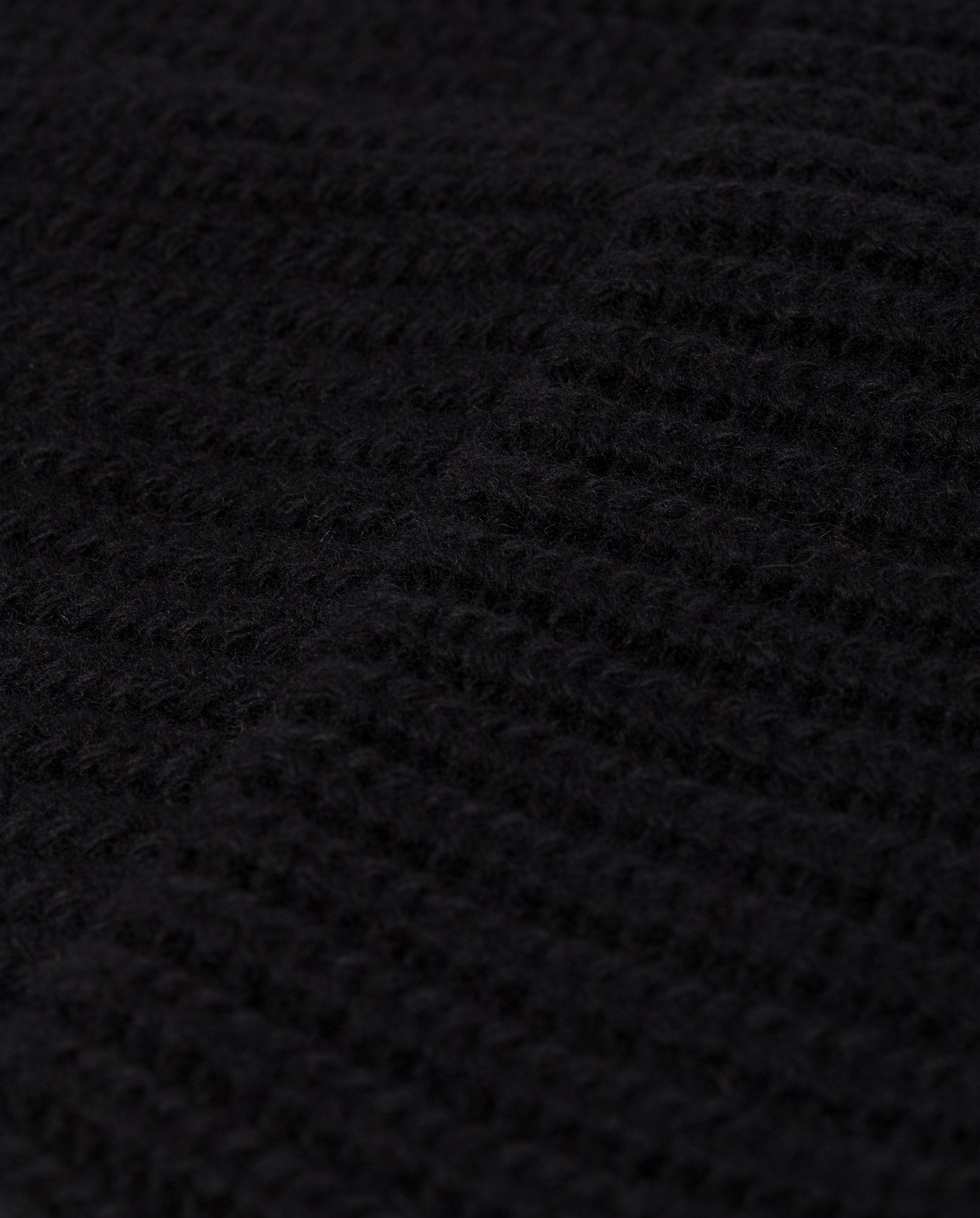 Close-up of the black heavy wool fabric with a ribbed knit pattern from the IVY OAK ALEXIA Beanie, ideal for an unlined knitted hat.