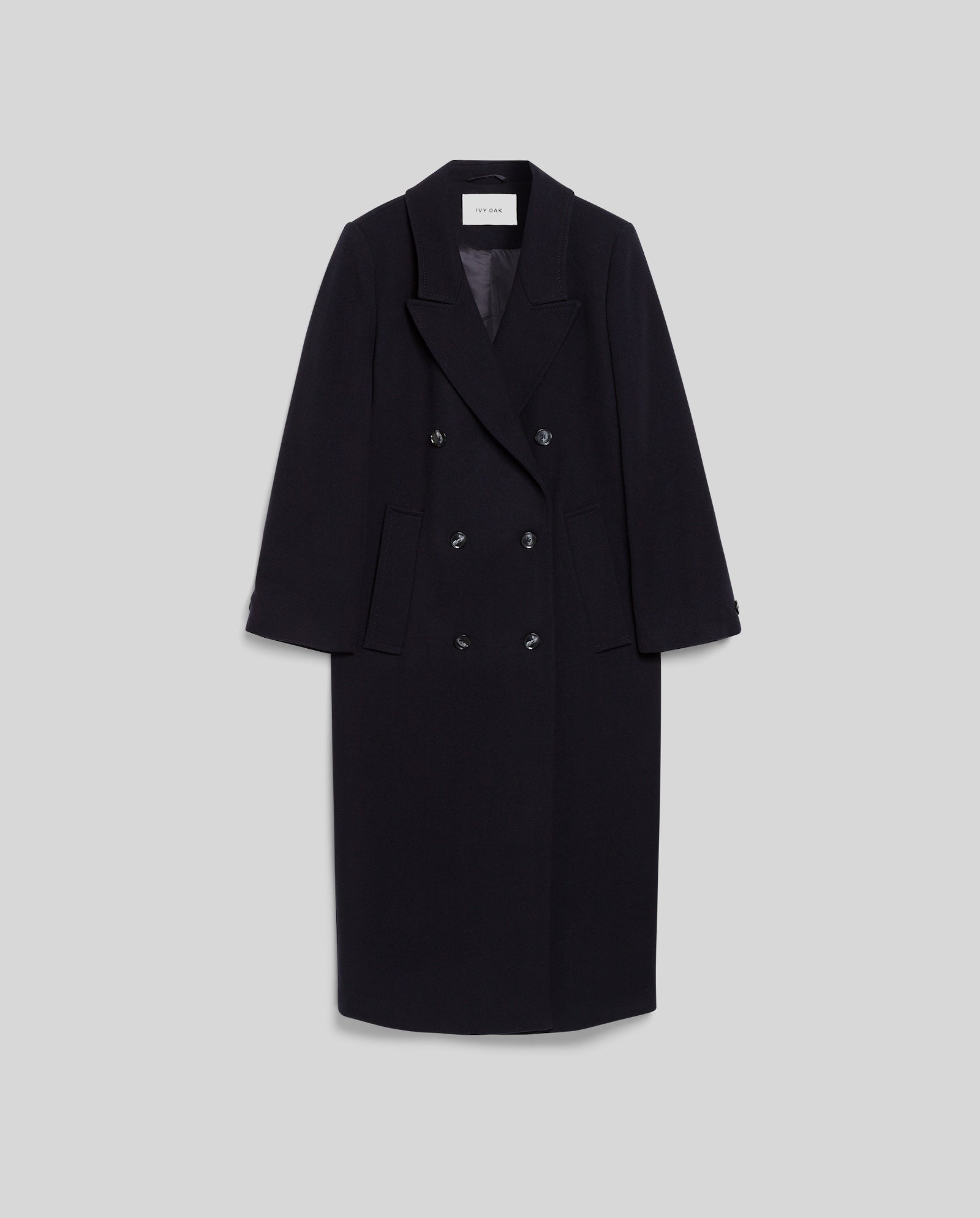 The IVY OAK CLEMENCE Coat is a long black oversized winter coat featuring wide lapels and four buttons in a classic double-breasted style, displayed against a plain gray background.