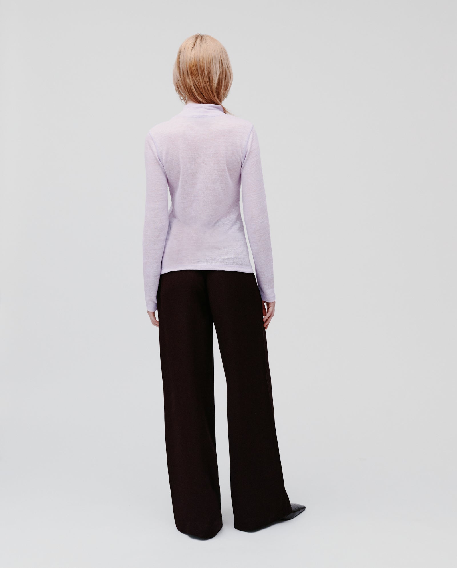 Person with blonde hair wearing the IVY OAK FELINE Top in light purple and black wide-leg pants, standing facing away.