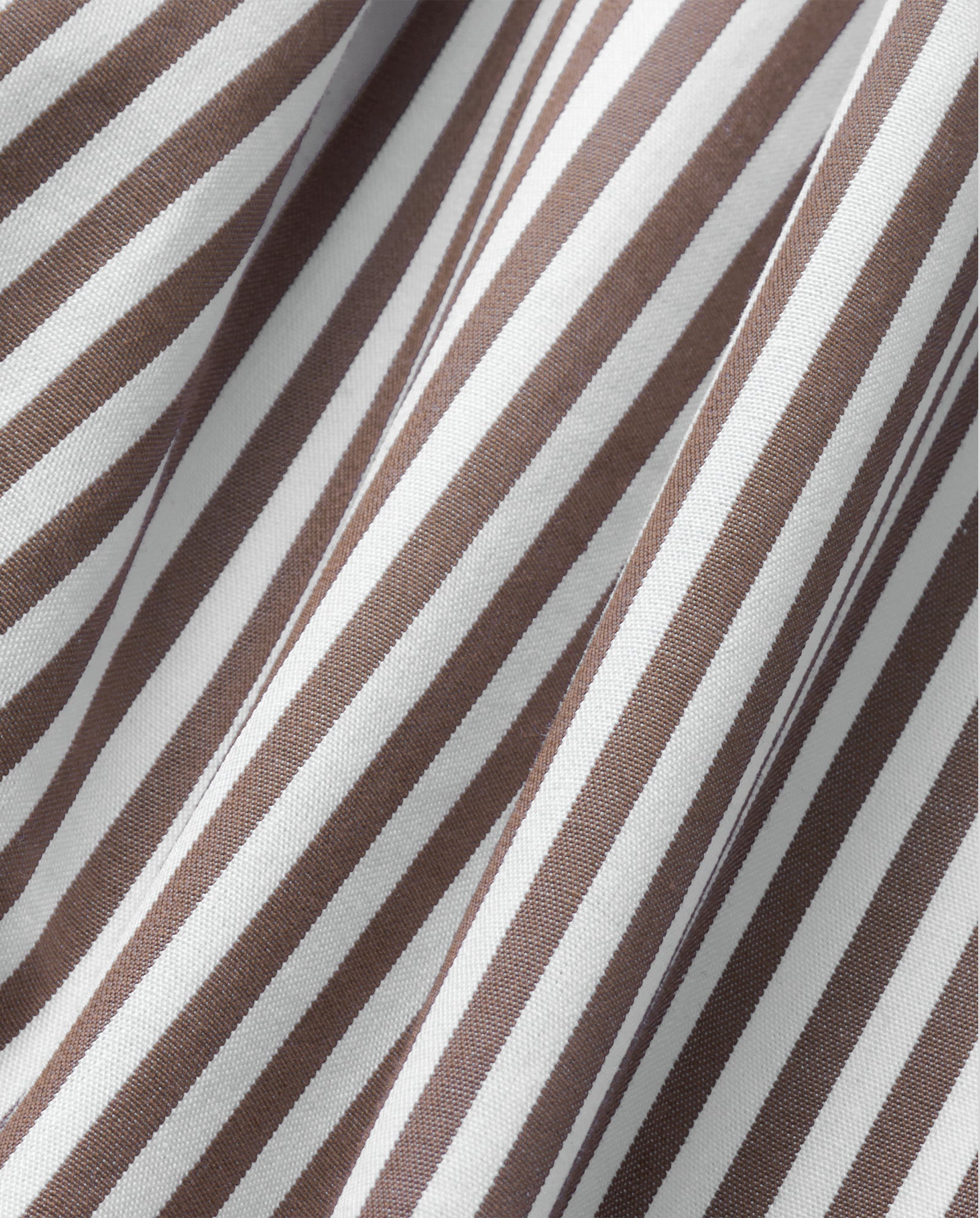 Close-up of brown and white striped fabric with folds and diagonal lines from the EVE Blouse by IVY OAK, reminiscent of an oversize shirt with classic button closure.
