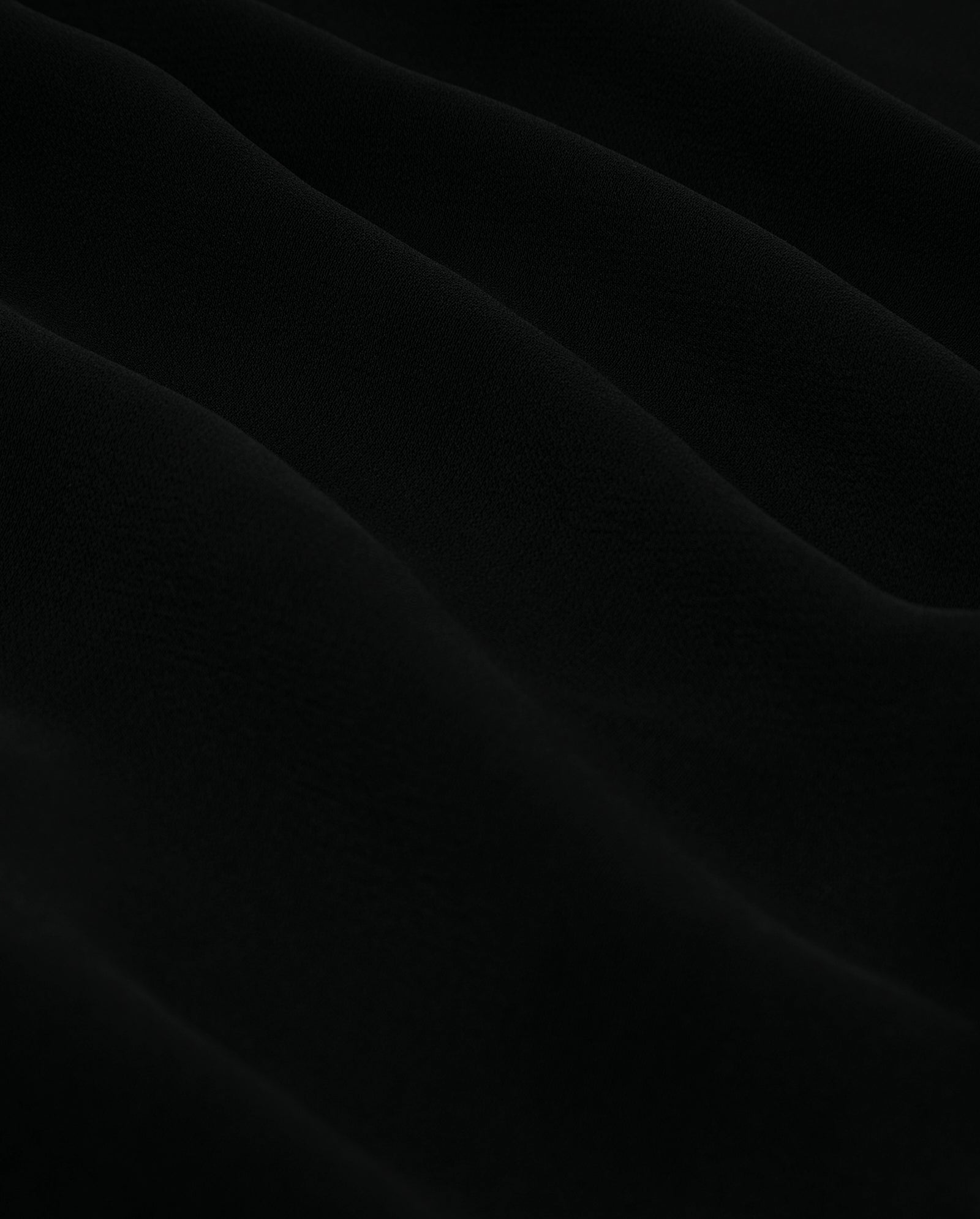 The TANSY Top by IVY OAK features wavy black crepe fabric with a soft, textured surface and gentle, undulating folds.