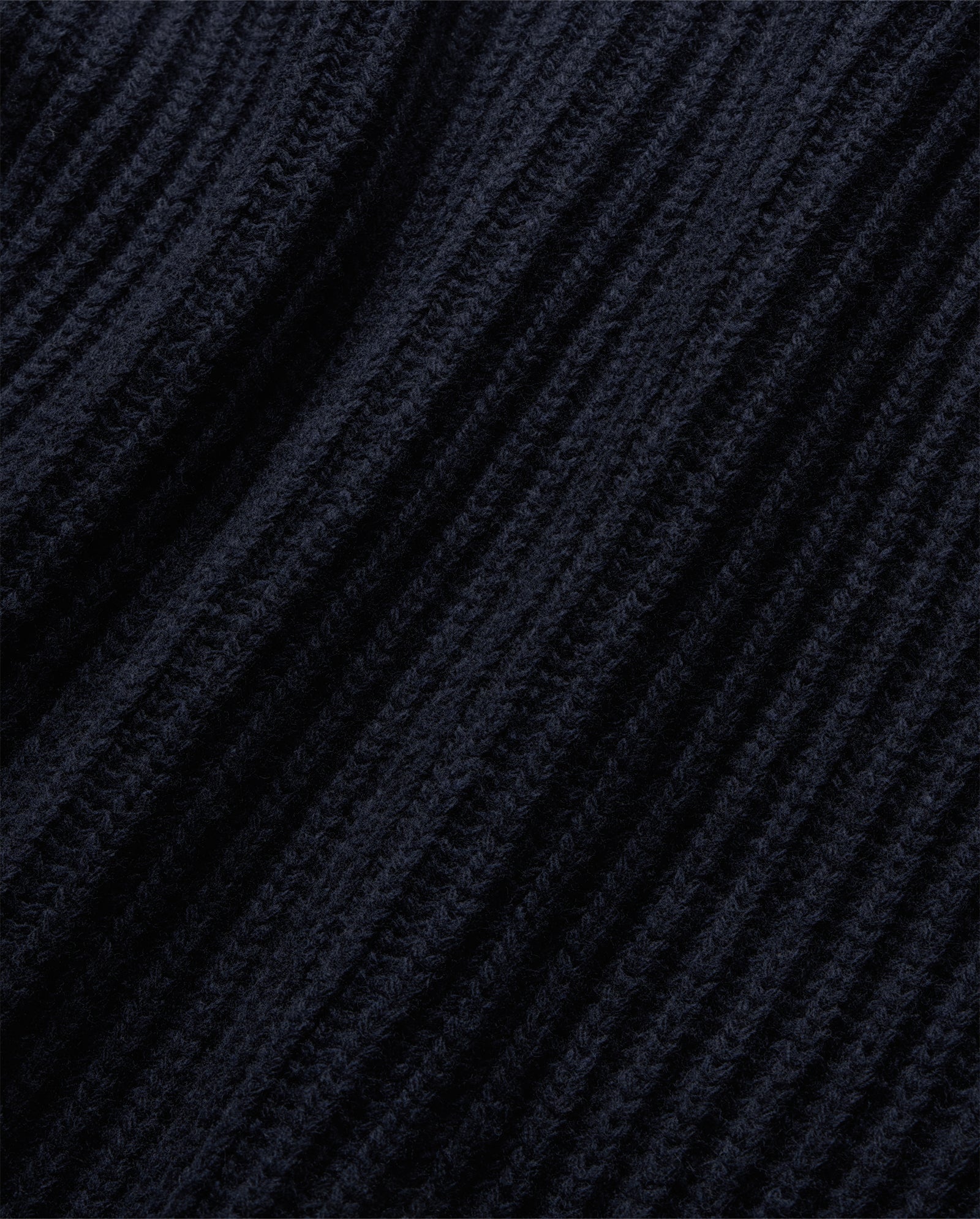 Close-up of dark ribbed knit fabric with diagonal textured lines, highlighting the cozy texture of the KYOMI Pullunder by IVY OAK.