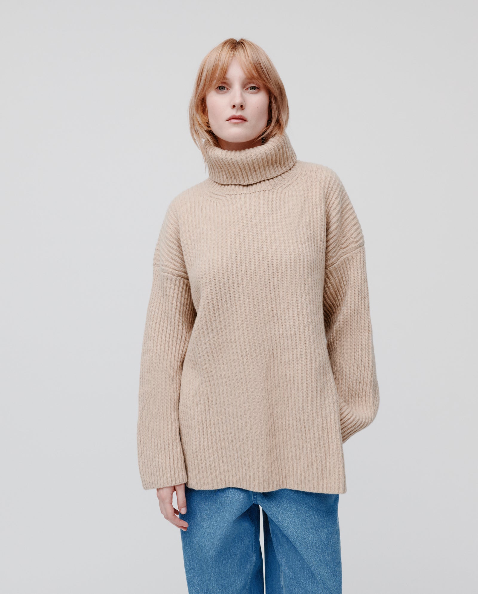 A person wears the KYOMI ANN Jumper by IVY OAK with blue jeans, standing against a plain light background.