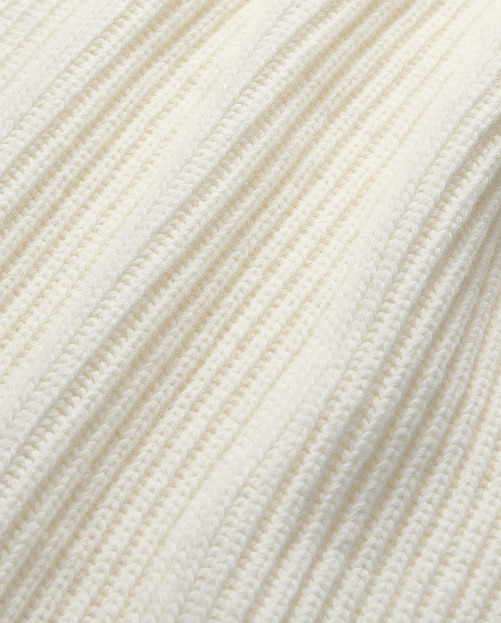 Close-up of the KYOMI ANN Jumper by IVY OAK, featuring cream-colored ribbed knit fabric with textured vertical lines—ideal for a cozy high-neck style.
