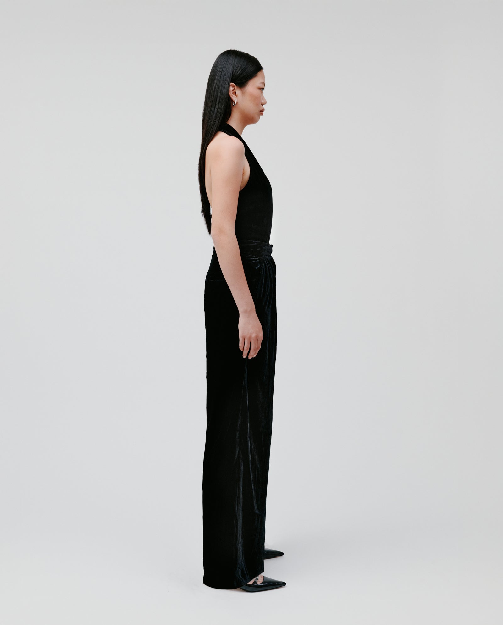 A woman in a black sleeveless top and IVY OAK PRESCILLIA ANN wide-leg velvet pants stands in profile against a plain white background.