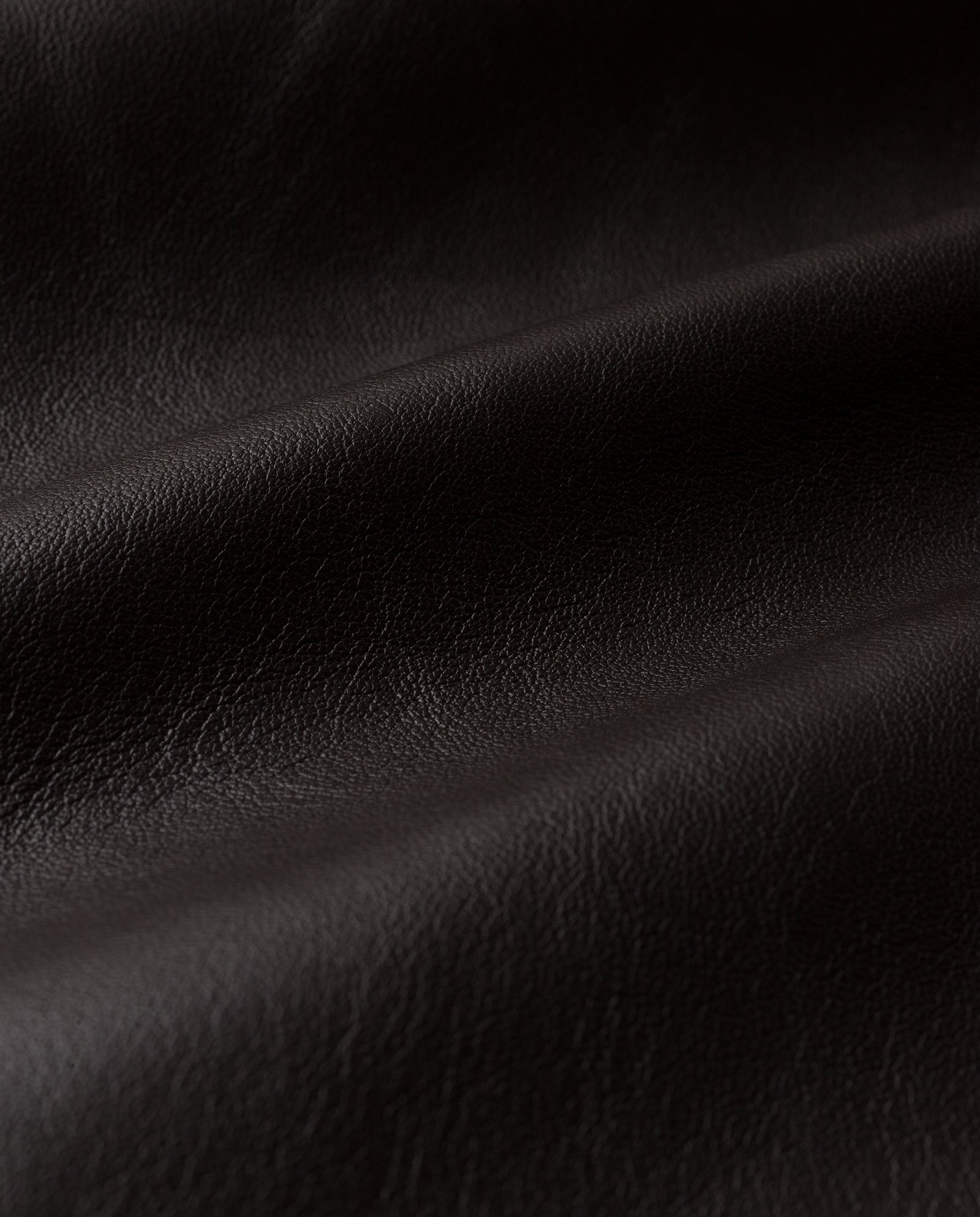 Close-up of black leather fabric with visible texture and soft folds—perfect for designing the IVY OAK LINDA Coat, whether as an oversized coat or a timeless double-breasted trench.