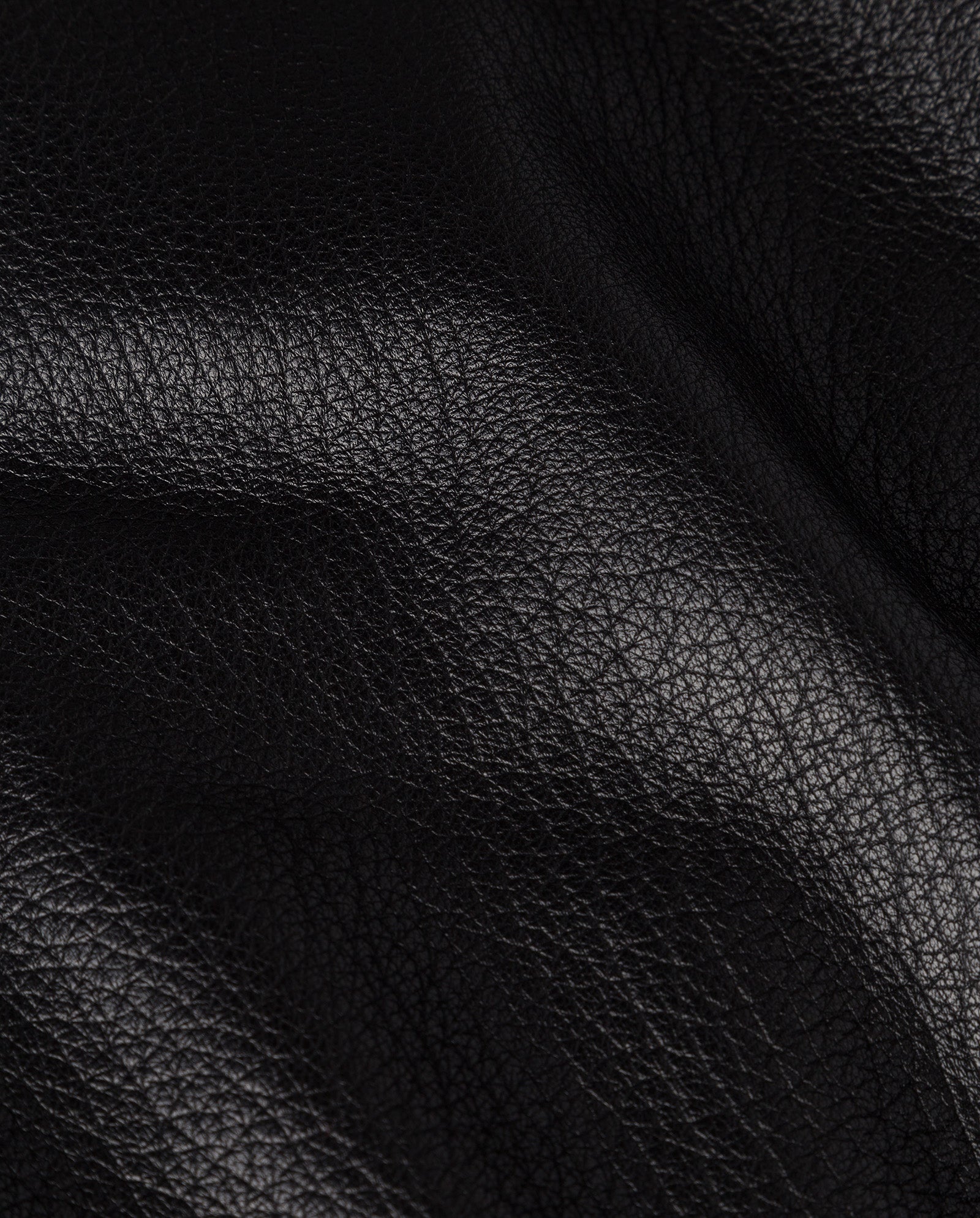 Close-up of black leather with visible grain and soft folds, highlighting the premium hide used in the oversized IVY OAK LARA Jacket.