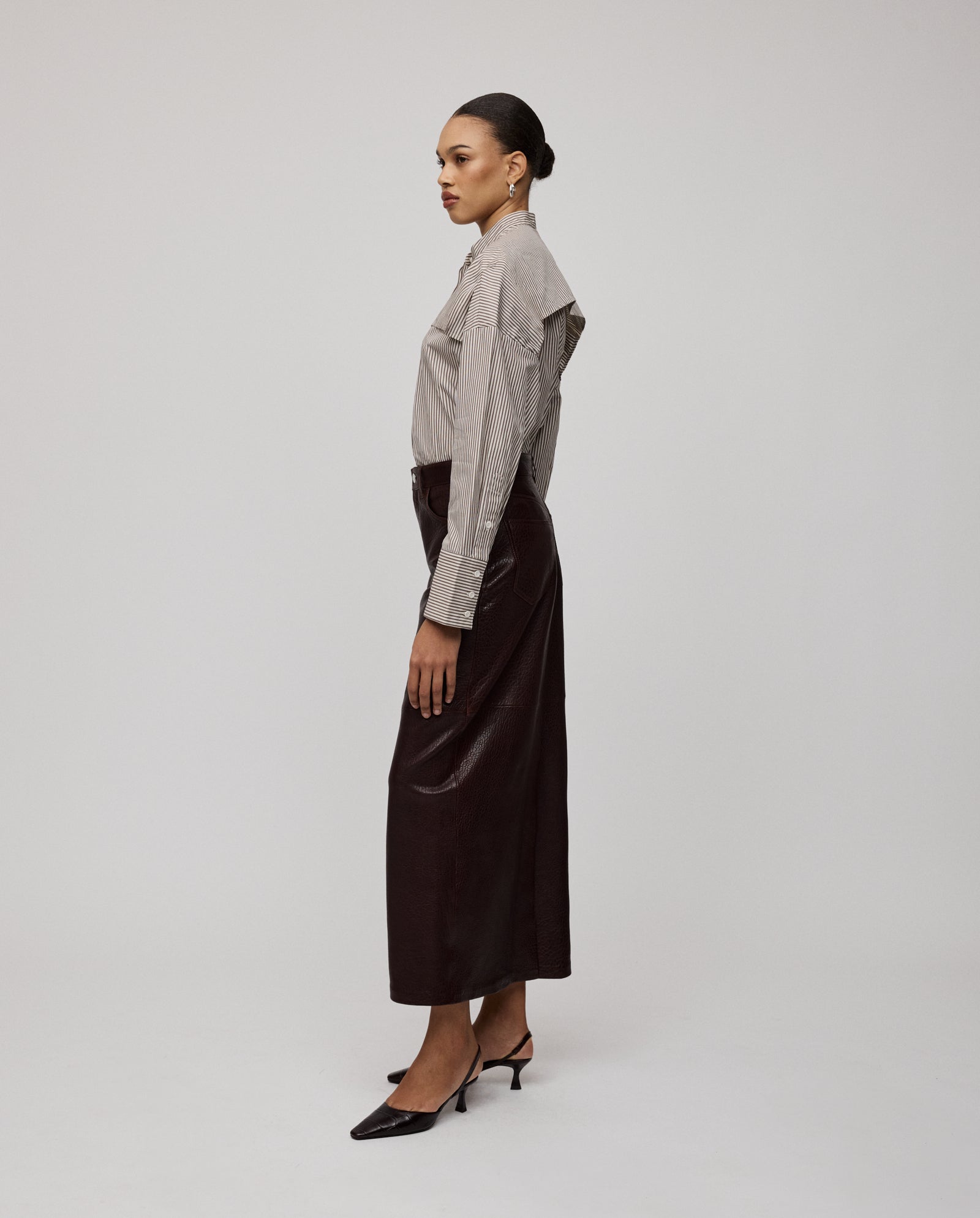 Woman in striped shirt, heels, and the IVY OAK LISANNE Skirt—an ankle-length A-line silhouette—standing in profile against a plain background.