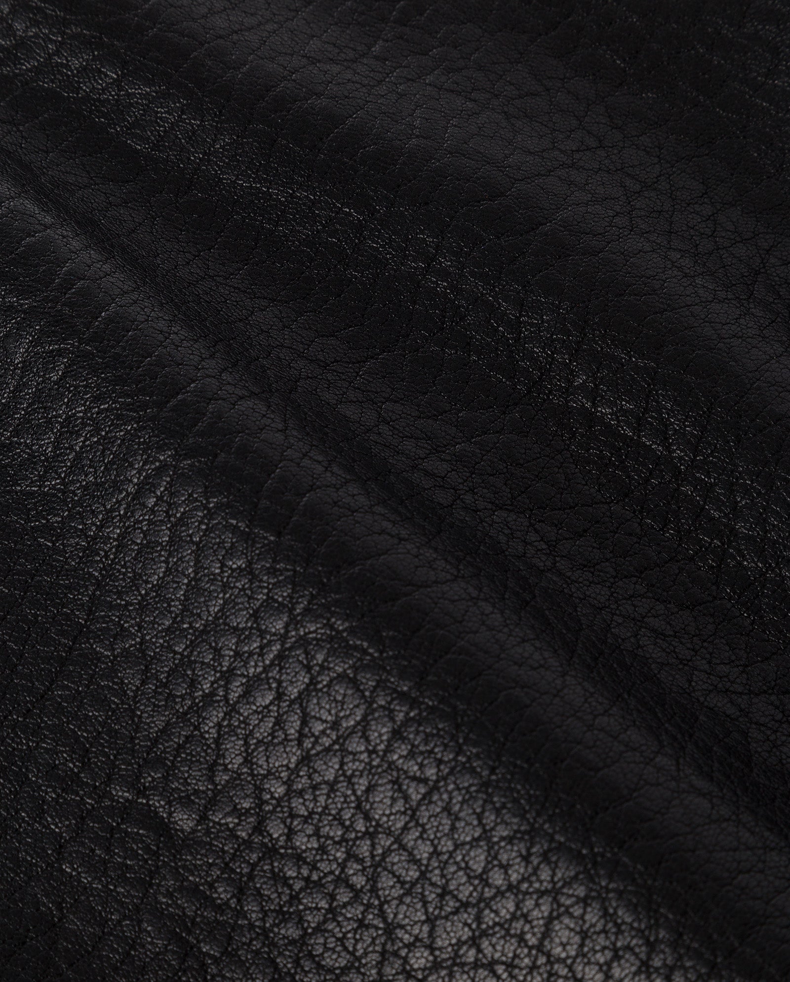 Close-up of the LILOU Skirt by IVY OAK, featuring black, textured leather from a premium hide with visible natural grain and a diagonal seam.