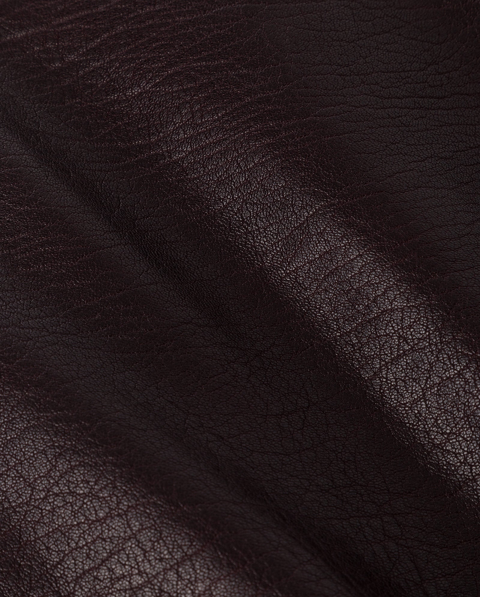 Close-up of dark brown, textured leather from premium hide by IVY OAK, showing natural creases and subtle shine—an elegant choice for the LILOU Skirt.